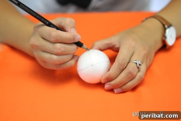Close-up of a Styrofoam ball with 8 sections meticulously drawn with a pencil, preparing the base for the fabric pumpkin ornament