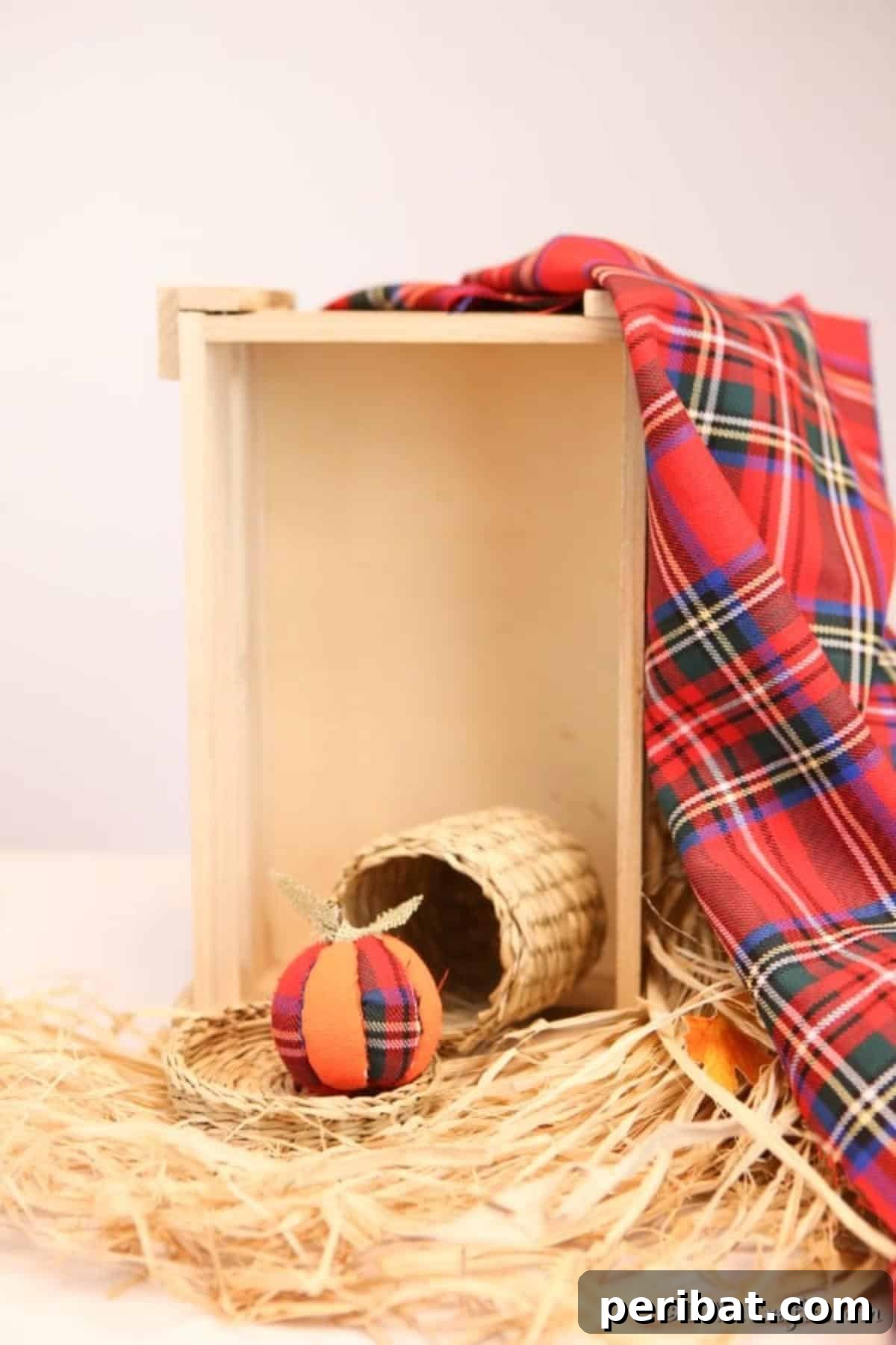 A completed fabric pumpkin ornament beautifully displayed, sitting on a bed of hay inside a rustic wooden box, perfect for harvest and fall decor