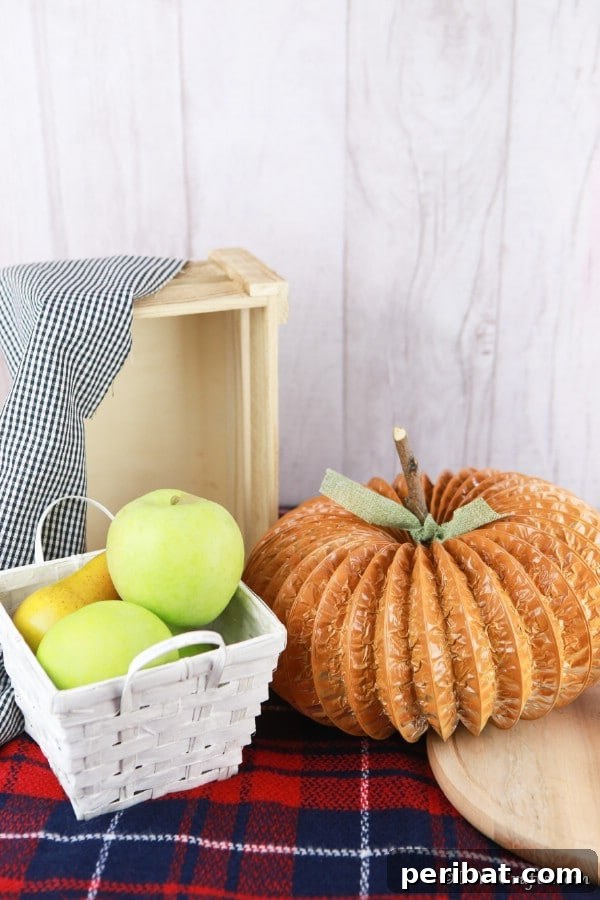 Easy DIY Dryer Vent Pumpkins Video Tutorial Included 18 A dryer vent pipe pumpkin decor piece sitting on a plaid fabric on a table with a basket in background