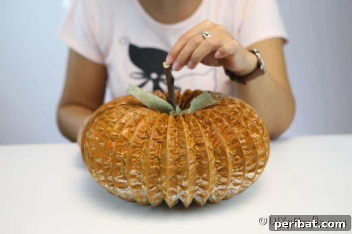 Easy DIY Dryer Vent Pumpkins Video Tutorial Included 9 Adding twig and leaf to the dryer vent pumpkin decor craft