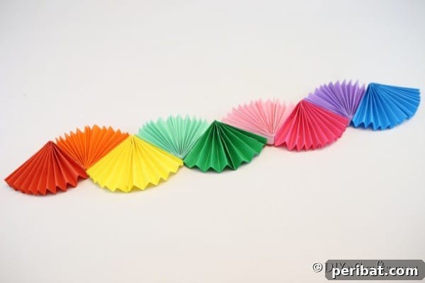 A complete rainbow paper fan party decoration on a white wall