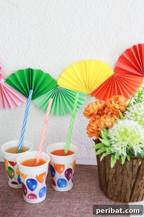 Up close picture of colorful paper fan garland on a wall behind buffet table