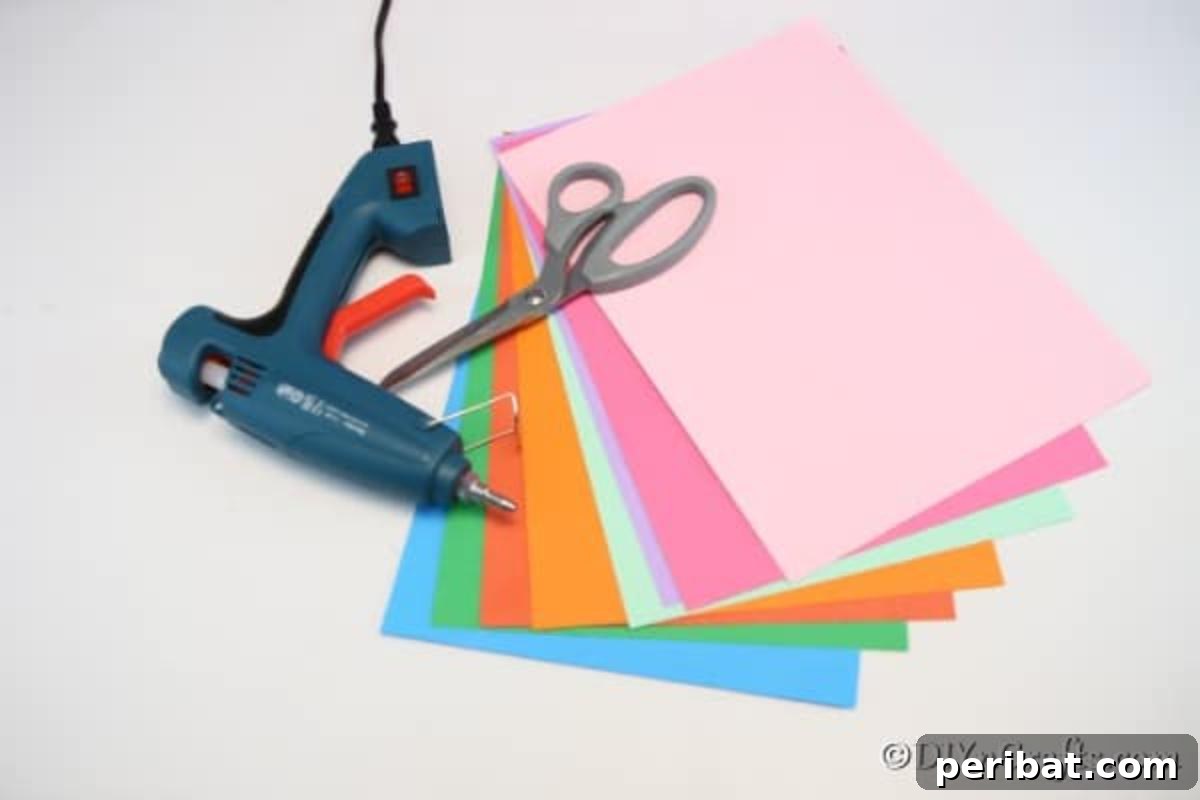A neatly organized collection of supplies including colorful construction paper, scissors, and a stapler, ready for making a paper fan garland decoration.