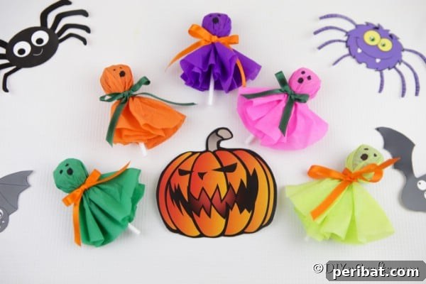 Halloween lollipop ghost craft treats laying on a white surface with spider and pumpkin stickers