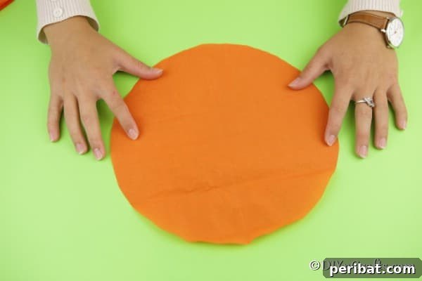 An orange circle of tissue paper laying on a green surface