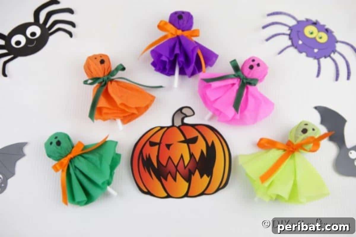 Halloween lollipop ghost craft treats laying on a white surface with playful spider and pumpkin stickers, ready to delight.