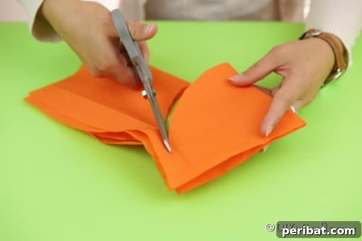 Hands carefully cutting tissue paper into perfect circles, preparing them to transform into adorable lollipop ghost crafts.