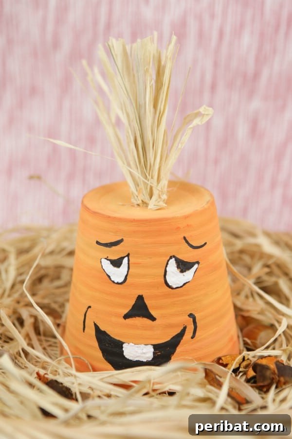 A charming finished silly-faced pumpkin planter resting on a bed of decorative hay, ready for fall display