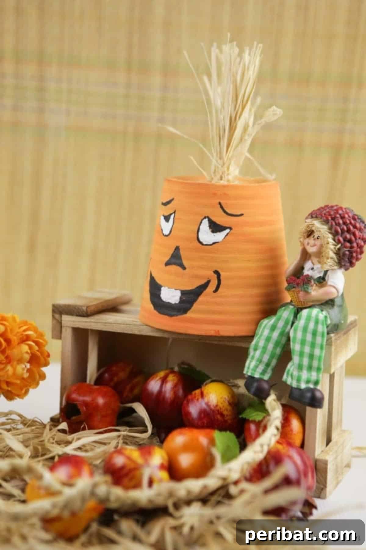 A beautifully crafted terra cotta pumpkin planter with a whimsical face, showcased on a wooden box amidst an assortment of other autumn decorations