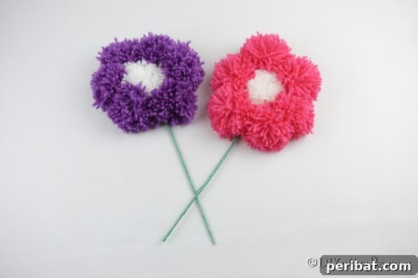 A purple and pink yarn pom pom flower sitting on a white surface