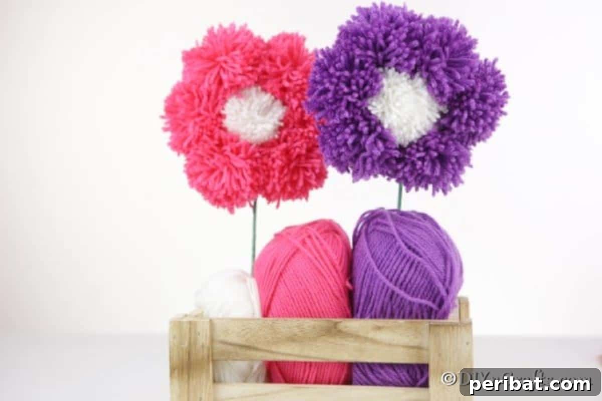Yarn Pom-Pom Floral Displays 3 Vibrant pink and purple yarn pom pom flowers beautifully arranged in a rustic wooden basket, perfect for cozy home decor.