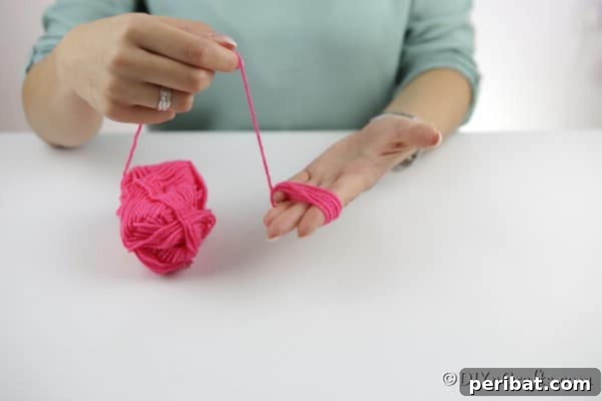 Yarn Pom-Pom Floral Displays 7 Detailed shot of yarn being wrapped around a hand to form the base of a fluffy pom pom flower petal.