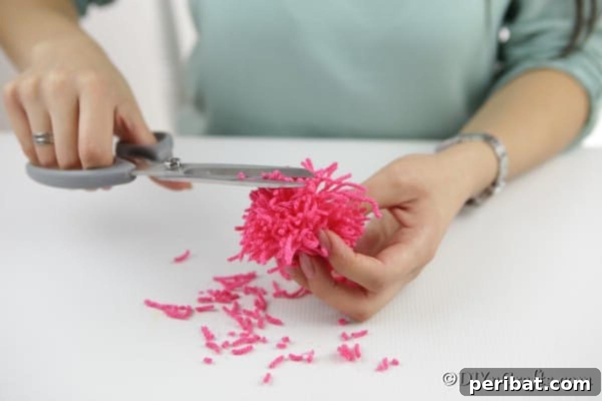 Yarn Pom-Pom Floral Displays 8 Close-up of yarn pom pom being trimmed with scissors to achieve a uniform, rounded shape, illustrating the finishing touch for a flower petal.