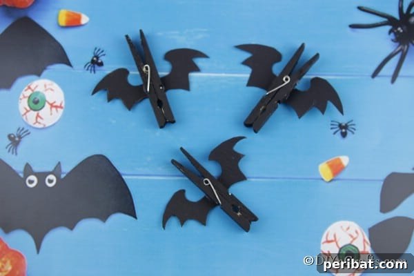 Spooky Fun Clothespin Bats for Halloween 15 Two completed Halloween bat clothespins, one featuring googly eyes, displayed against a vibrant blue background