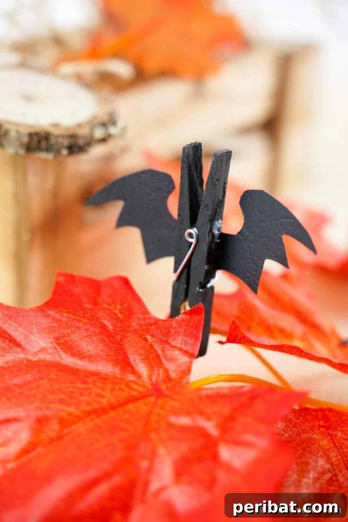 Spooky Fun Clothespin Bats for Halloween 4 A charming Halloween bat clothespin resting on an orange artificial autumn leaf