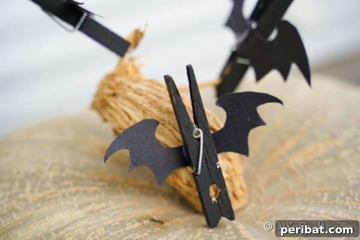 Spooky Fun Clothespin Bats for Halloween 5 A handmade clothespin bat with googly eyes resting on a decorative mini pumpkin