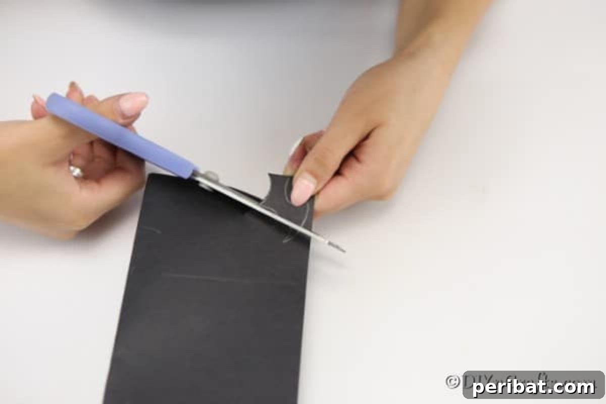 Spooky Fun Clothespin Bats for Halloween 11 Hand drawing a bat wing shape onto black paper with a pencil before cutting