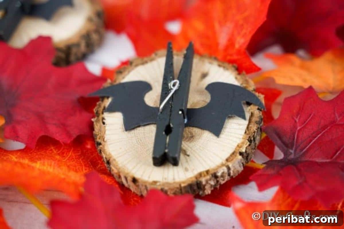 Spooky Fun Clothespin Bats for Halloween 14 Hand gluing a black bat wing onto the side of a reassembled black clothespin