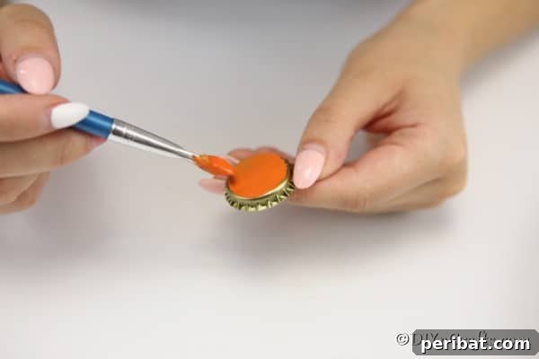 Painting a bottle cap orange for a pumpkin magnet