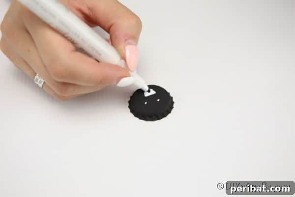 Drawing a face on a black bottle cap to create a spider