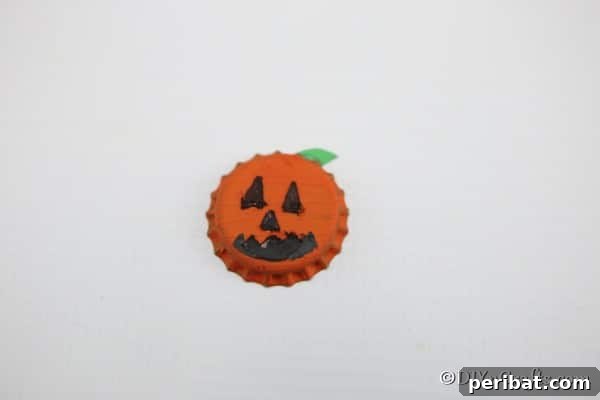A completed orange pumpkin fun magnet made from bottle caps