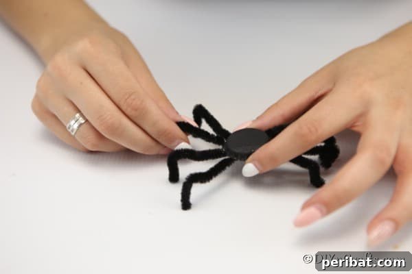Gluing legs on the underside of a bottle cap to create a spider