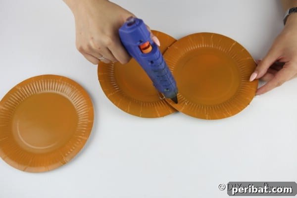 Fall Paper Plate Pumpkin Fun 9 The process of gluing two paper plates together at the back of a central plate, forming the basic structure of the paper plate pumpkin.