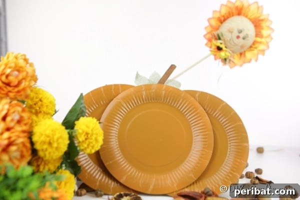 Fall Paper Plate Pumpkin Fun 13 A completed paper plate pumpkin craft, elegantly displayed alongside other autumnal flowers and decorative elements, showcasing its integration into fall home decor.