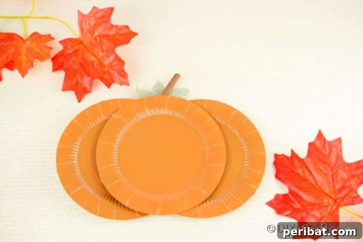 Fall Paper Plate Pumpkin Fun 5 A beautifully finished paper pumpkin craft, carefully laid on a clean white surface, showcasing its vibrant orange color and neat construction.