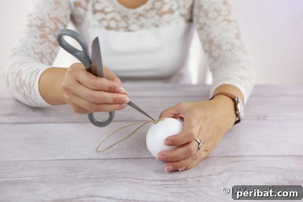 Adding the twine hanging piece to the middle of the styrofoam ball for a rustic ornament