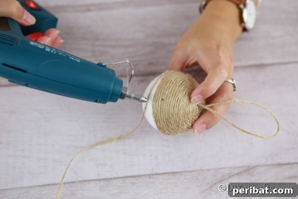 Gluing twine to the styrofoam ball for a christmas ornament