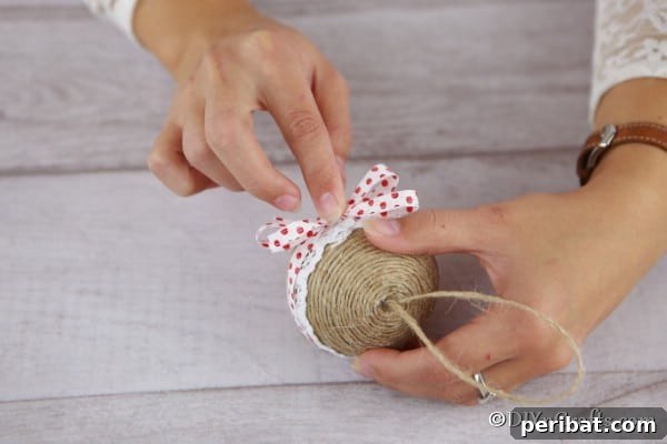 Adding a ribbon bow to the front of the rustic ornament