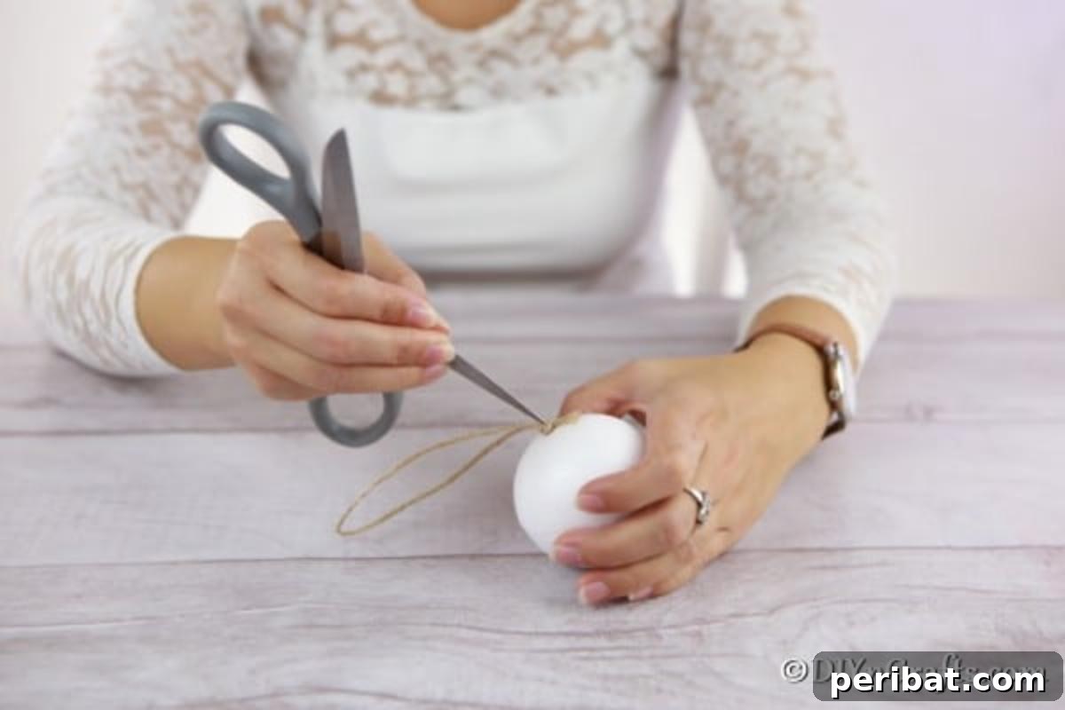Adding the twine hanging piece to the middle of the styrofoam ball for a rustic ornament