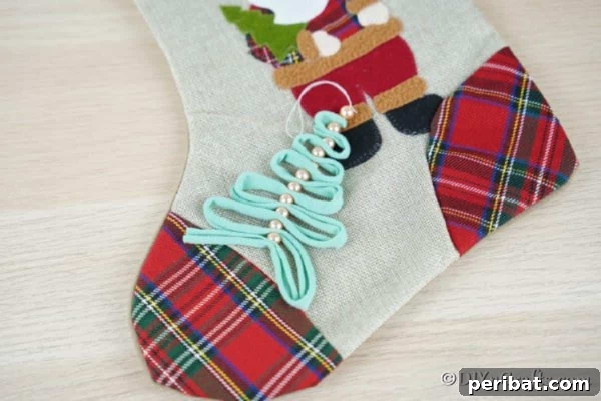 A ribbon and peral handmade Christmas ornaments idea laying on a Christmas stocking