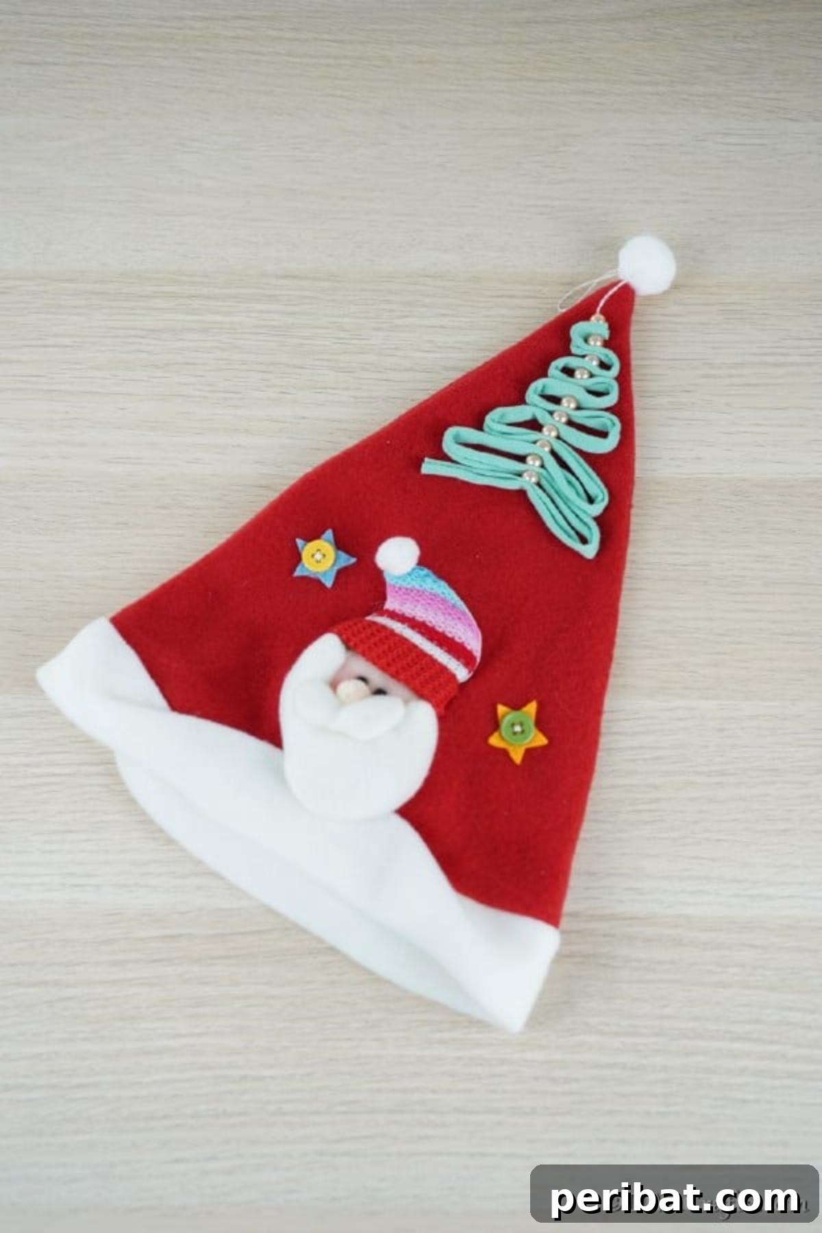 A pearl and ribbon christmas tree ornament laying on a santa hat