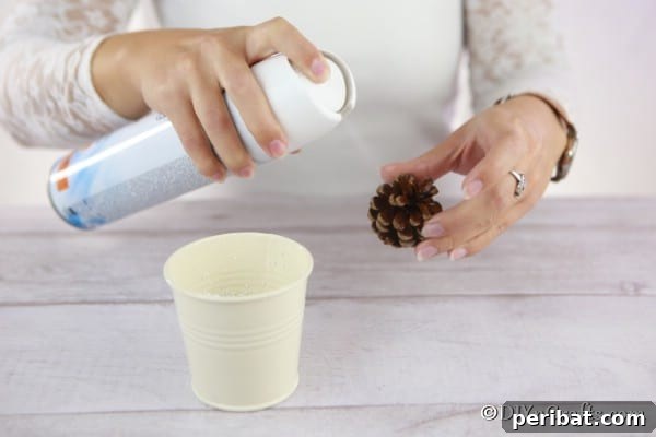 Tiny Pinecone Christmas Ornament 15 Spraying inside a pine cone to add fake snow for a DIY Christmas ornament