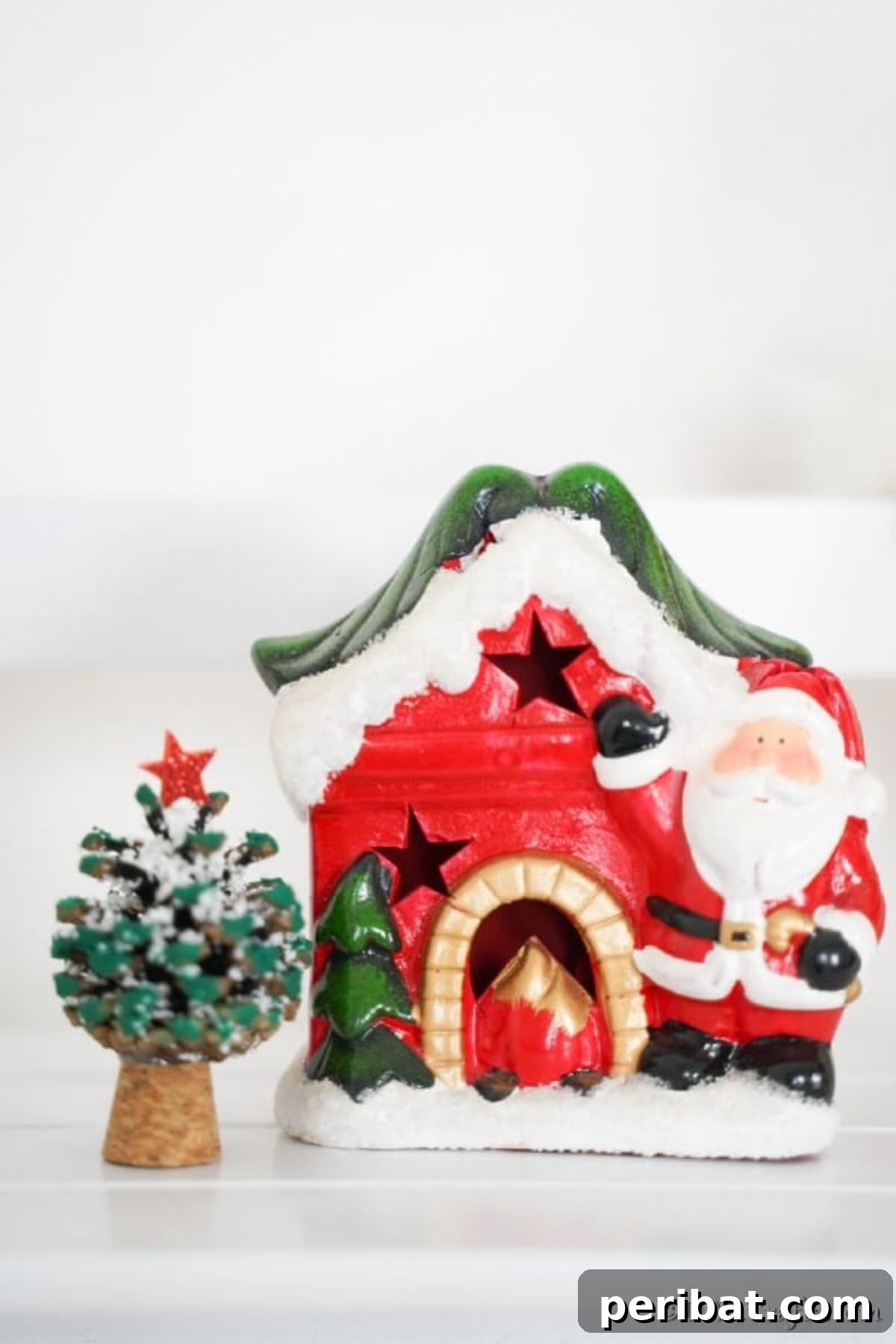 Tiny Pinecone Christmas Ornament 6 A holiday pine cone Christmas tree ornament sitting next to a Santa house decoration on a counter