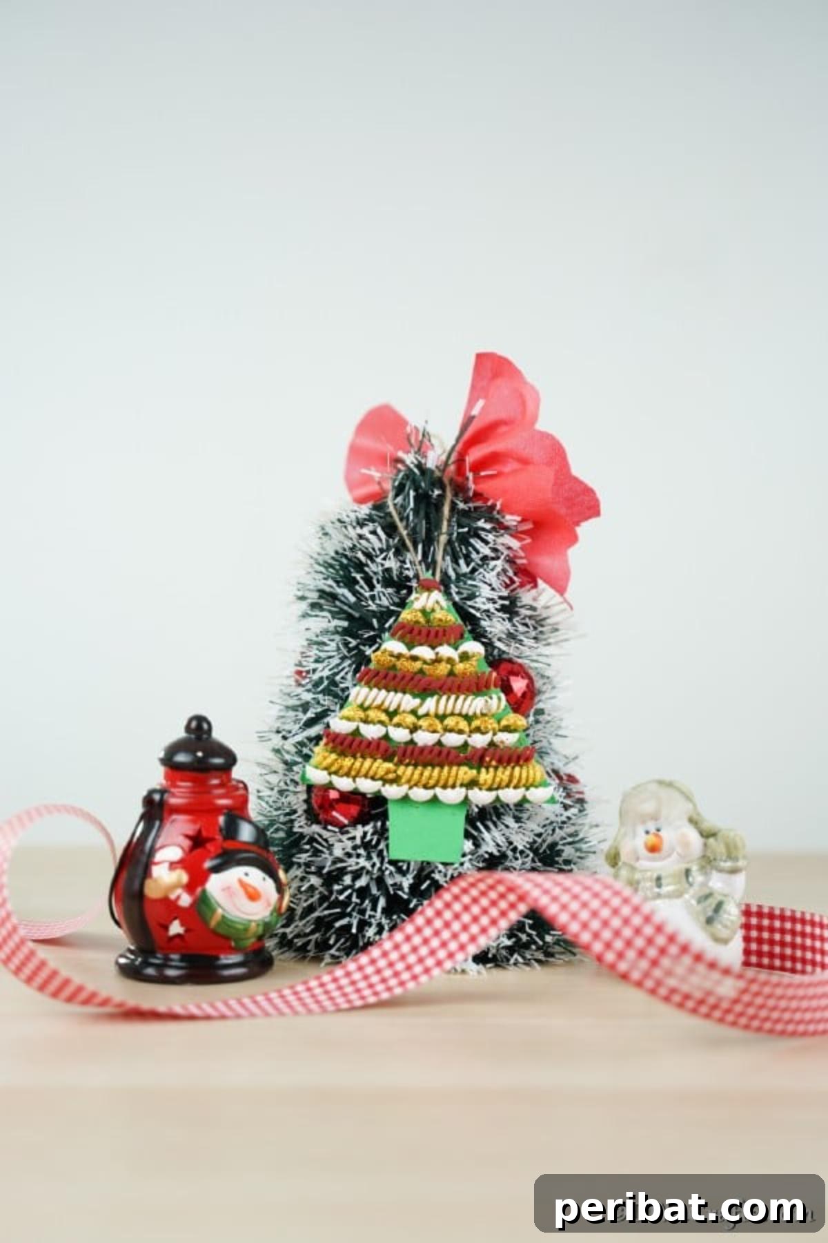 Whimsical Pasta Christmas Tree Decor 14 A small tree with a pasta Christmas tree decoration hanging on the front with red ribbon, showcasing the finished product