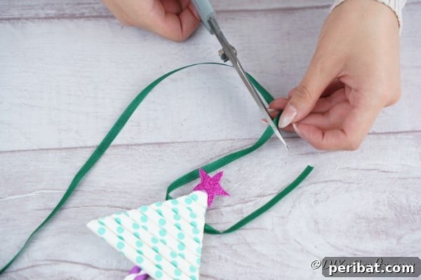 Adding a ribbon to the top of the paper Christmas tree craft
