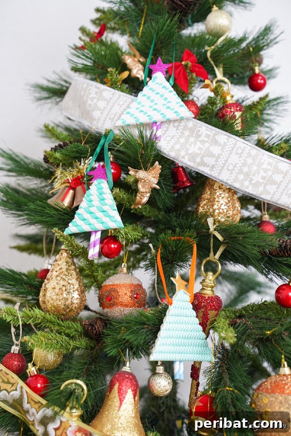 A Christmas tree with paper Christmas tree ornaments hanging on it with ribbon