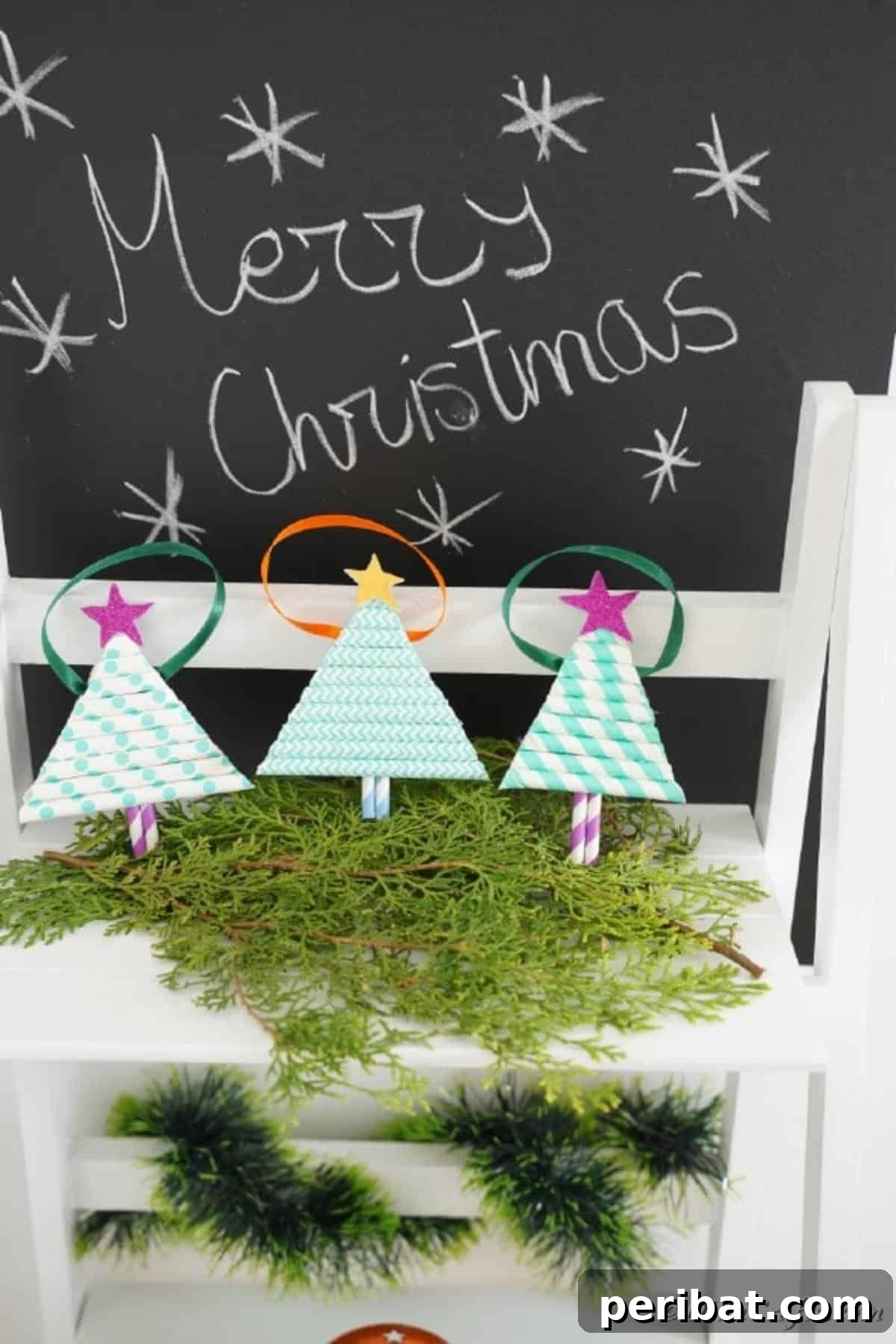 Paper Christmas tree ornaments displayed on a shelf with holiday greenery