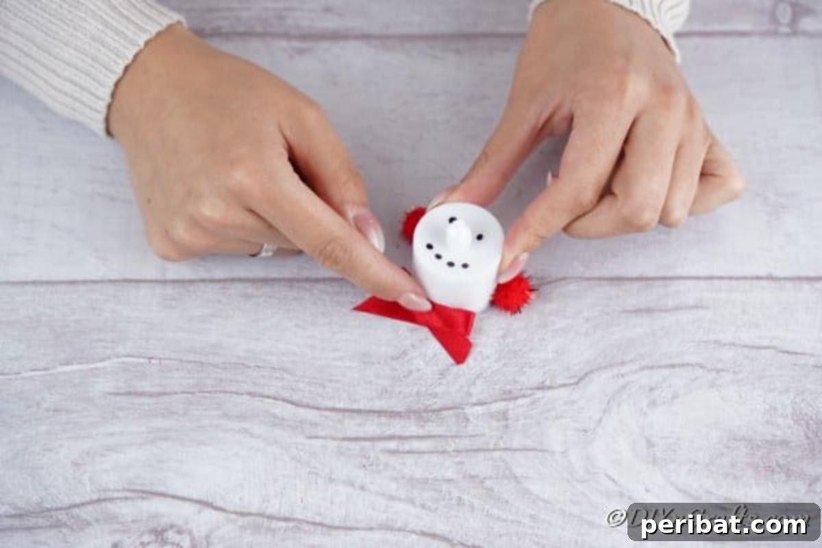 Adding a decorative bow to a Santa Christmas candle craft, enhancing its festive appeal