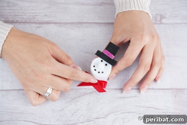 Attaching a satin bow to the bottom of a christmas candle