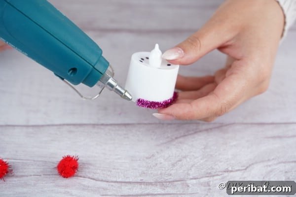 Gluing purple ribbon to base of santa candle