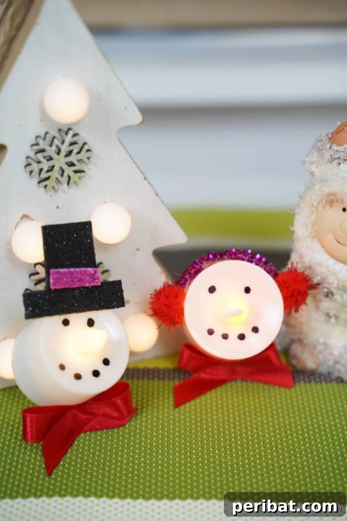 Snowman and Santa Christmas candles displayed charmingly on a green table, ready for holiday festivities