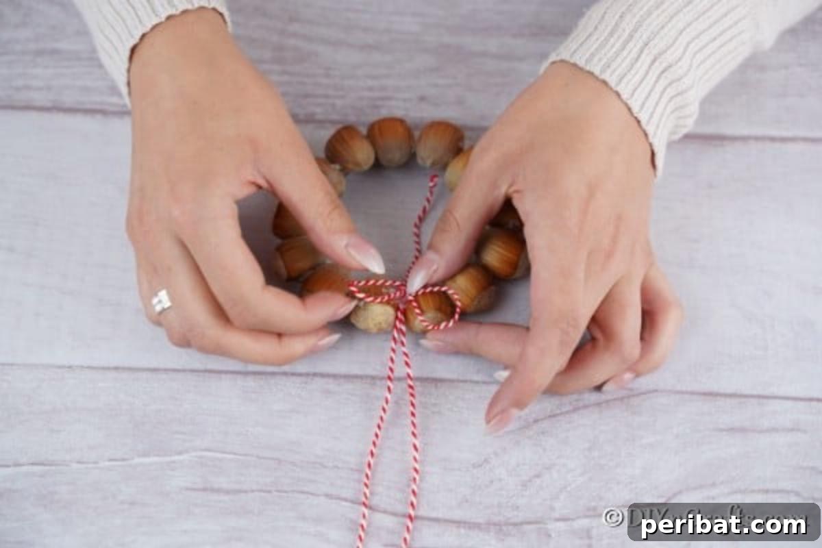 Handmade Rustic Hazelnut Christmas Ornaments 9 Detailed image of twisting and attaching the rope hanger to the hazelnut wreath ornament, ensuring secure suspension.