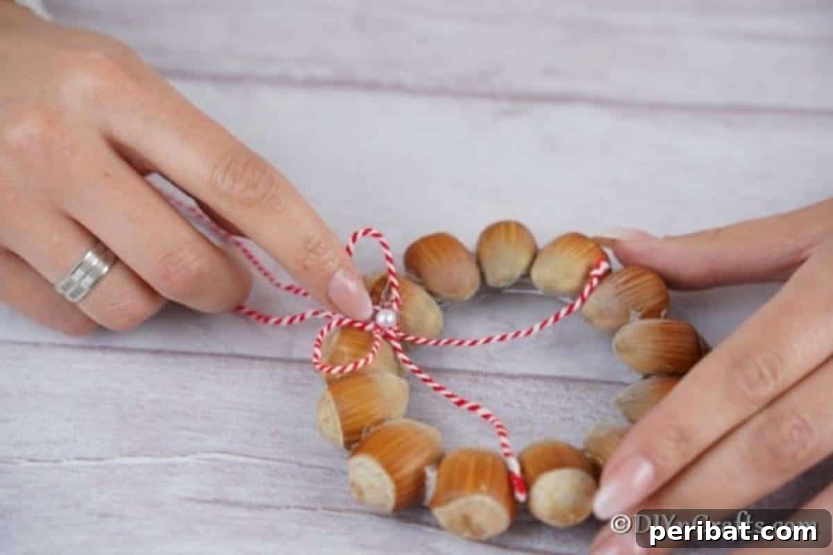 Handmade Rustic Hazelnut Christmas Ornaments 10 The final touch: adding a delicate small bow adorned with a decorative pearl to the center of the rustic hazelnut wreath.