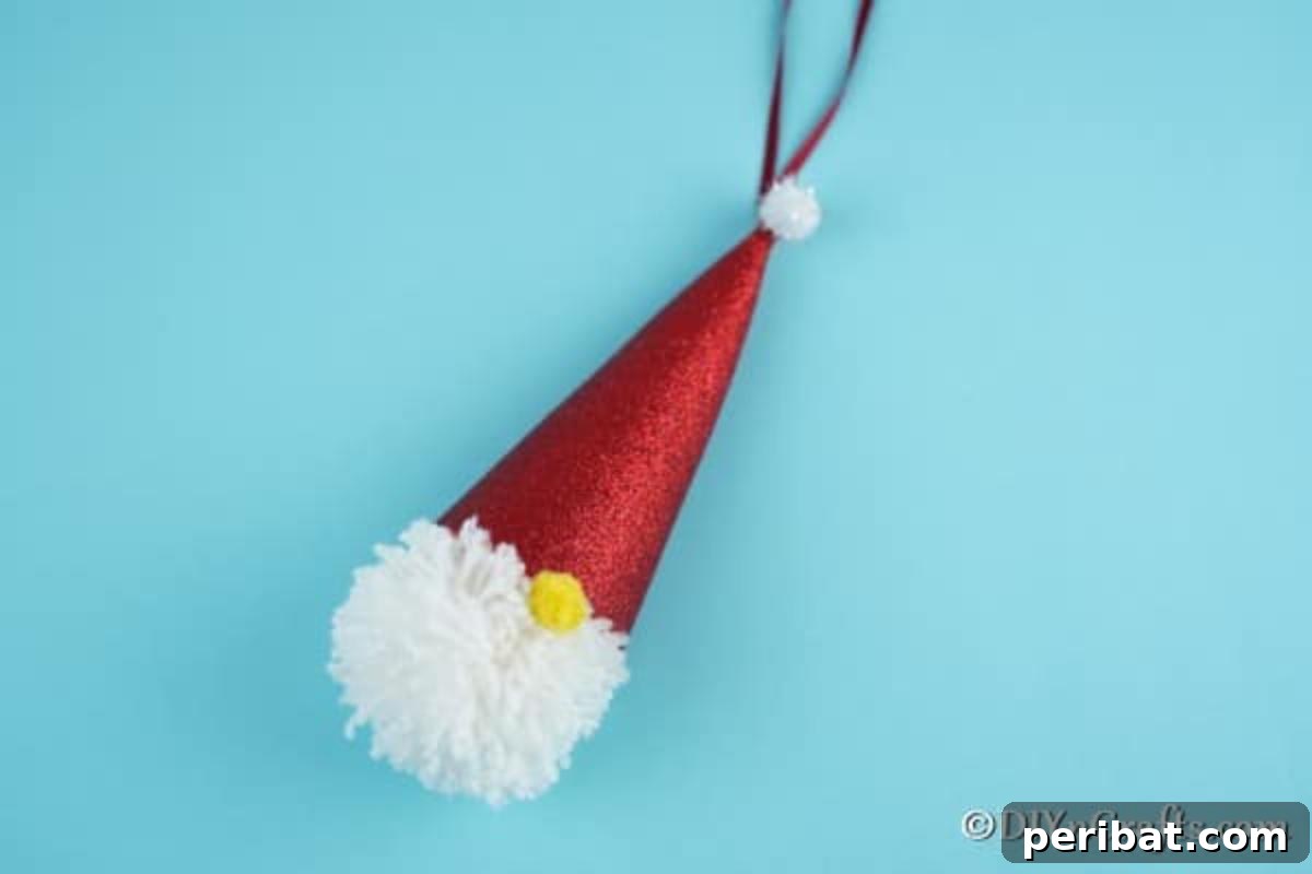 Cozy Pom-Pom Gnomes: Whimsical Holiday Tree Charms 14 A simple Christmas gnome ornament decoration laying on a blue surface