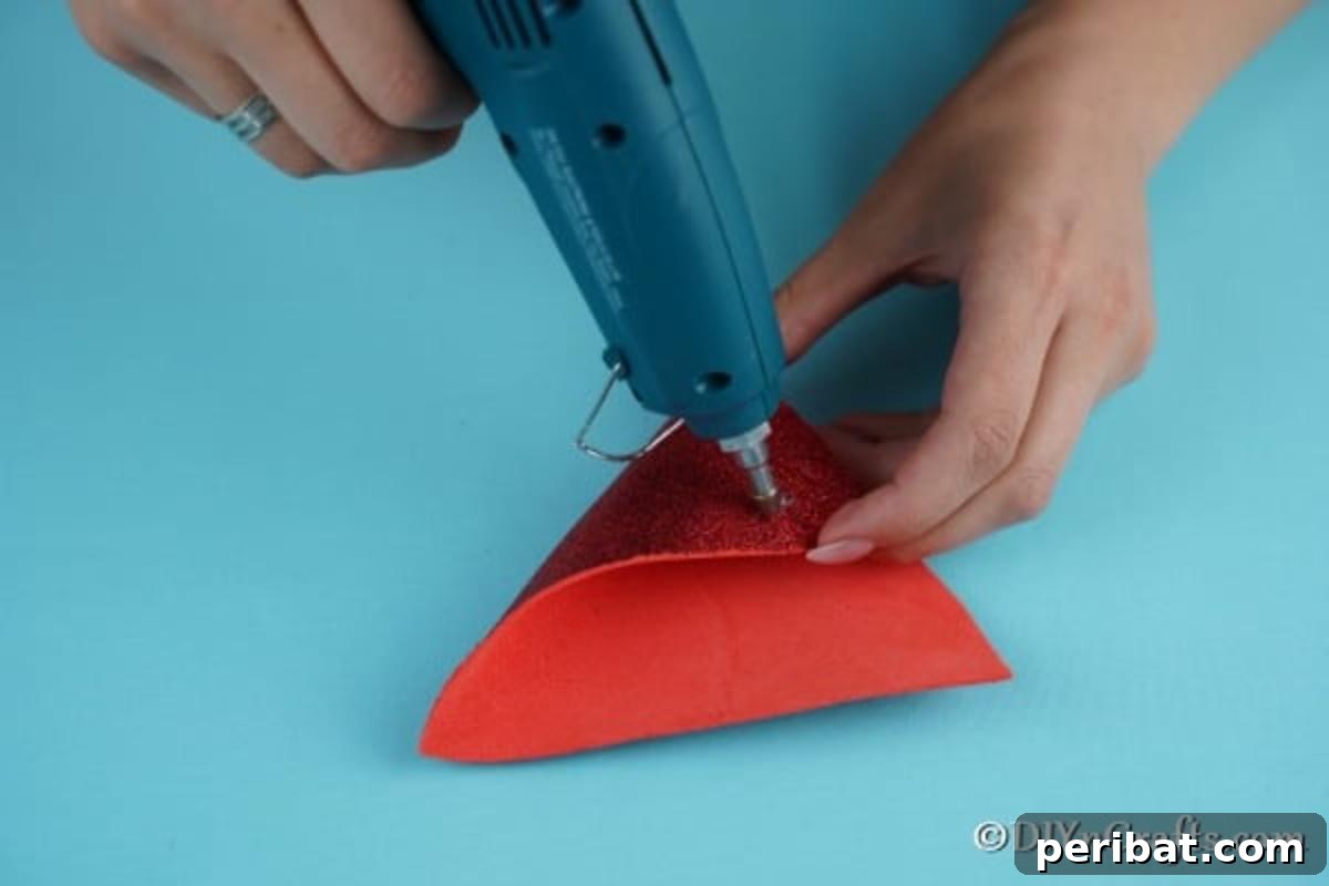 Cozy Pom-Pom Gnomes: Whimsical Holiday Tree Charms 10 Gluing the foam board pieces together to create cone hat for Christmas gnome