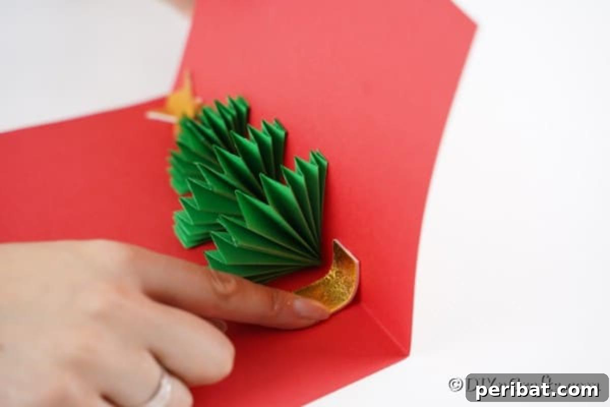 Gluing a gold star at the top of a 3D Christmas tree card